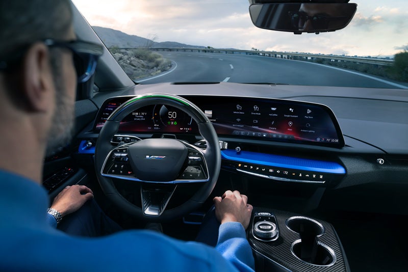 Front View of the 2026 OPTIQ-V Driving Through the Dusk Utilizing its Headlights | Crown Cadillac in Watchung NJ