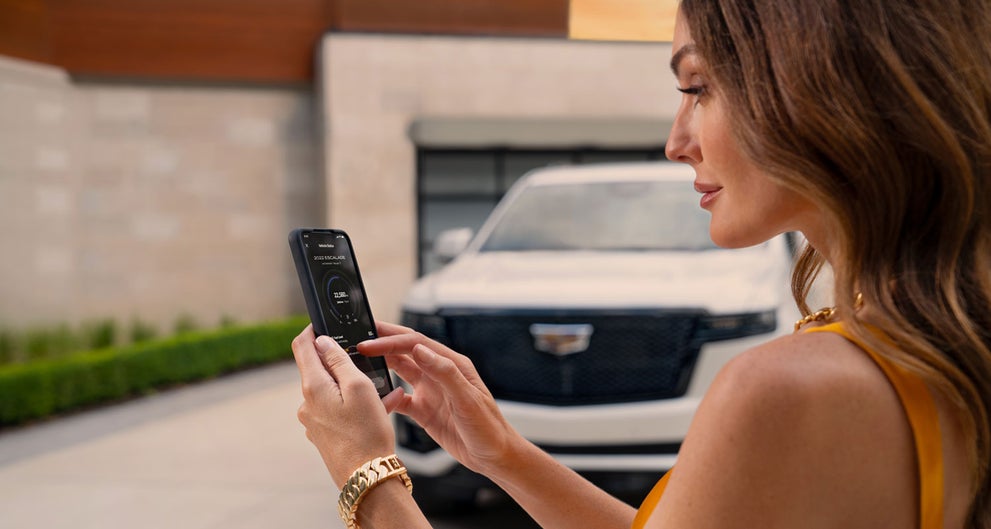 lady checking her mobile with a Cadillac vehicle background | Crown Cadillac in Watchung NJ